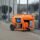 Generador eléctrico portátil naranja funcionando en exteriores junto a un edificio, ideal para aplicaciones industriales y de construcción.
