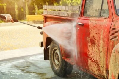 Hidrolavadora de alta presión limpiando un vehículo cubierto de lodo, removiendo suciedad pesada con un chorro potente de agua.
